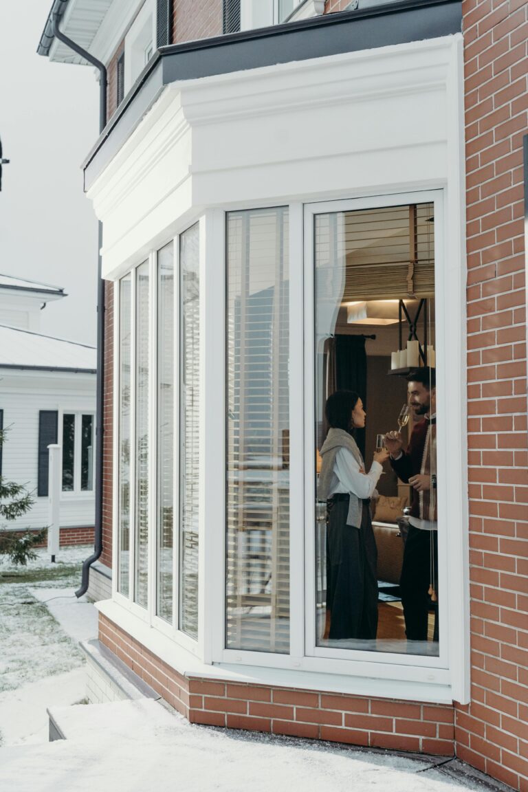 Window Cleaning A couple enjoying wine indoors through large window in a modern house setting.